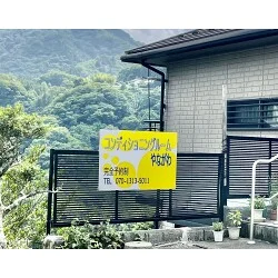 背景の自然に黄色の看板が一際目を引く整体院様のプレート看板を製作いたしました。