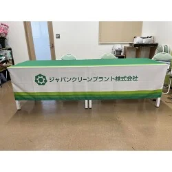 グリーン帯に社名が映えるクリーンエネルギー機器製造会社様のオリジナルテーブルクロスを製作いたしました。